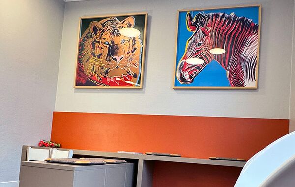 2 abstrakt gemalte Bilder hängen an der Wand im Warteraum. Links ein Tiger, rechts ein Zebra